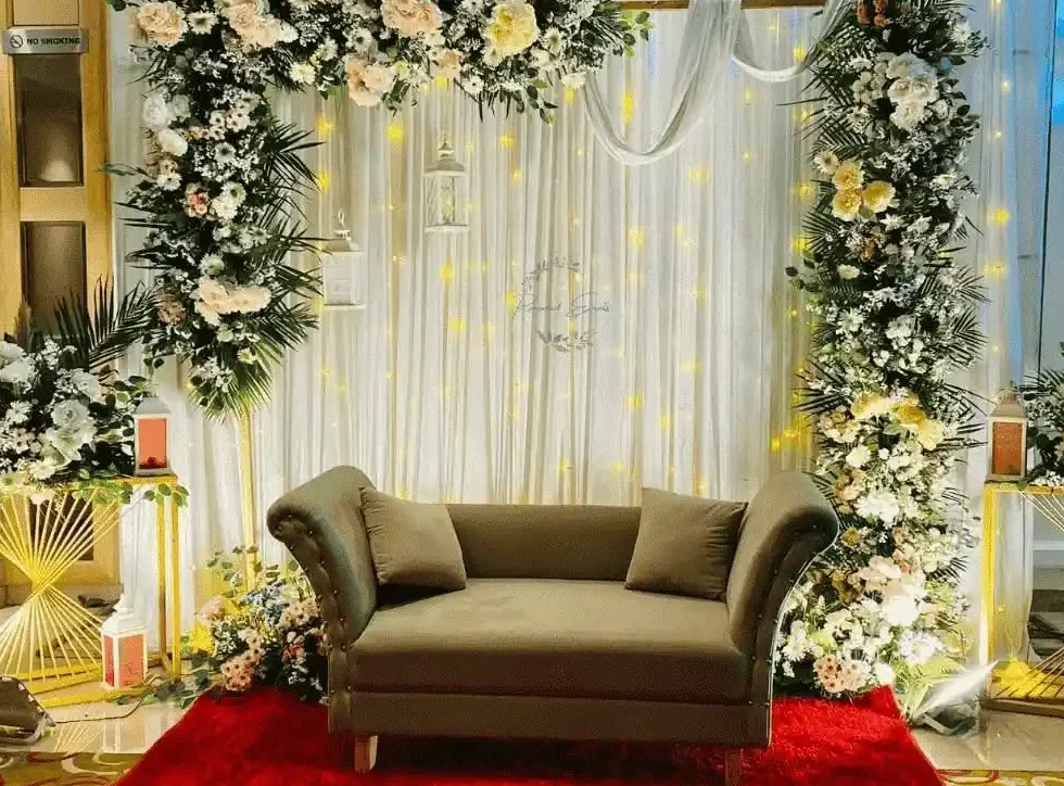Luxury floral wedding stage decoration featuring fresh flowers, elegant backdrop, and decorative lighting.