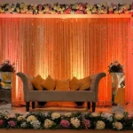 Modern wedding stage decoration with LED backdrop, elegant flowers, and luxury seating arrangement.